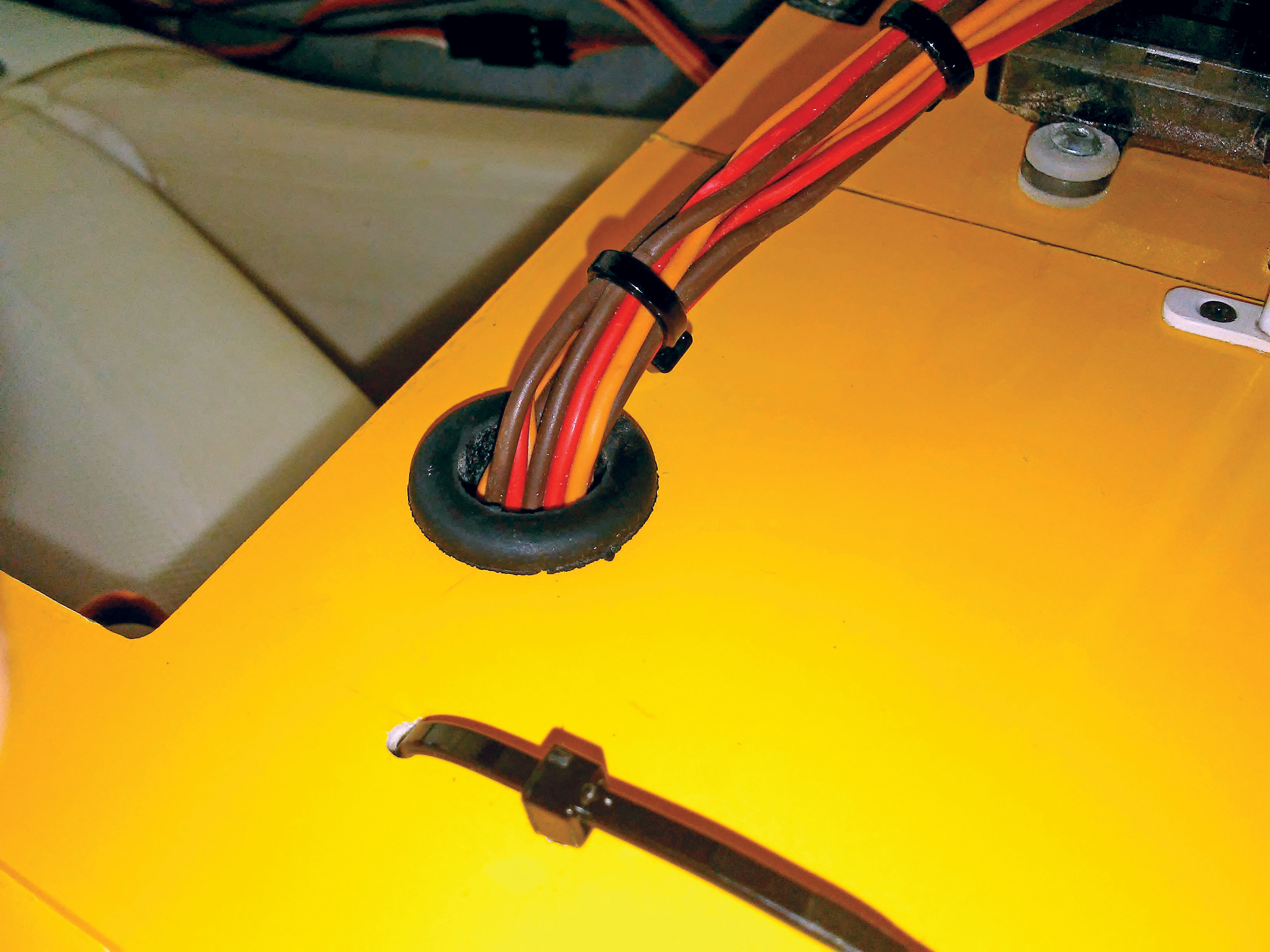 this is an example of how to clean up your servo harness by using a simple hardware store grommet that protects the servo extensions from the abrasive fiberglass