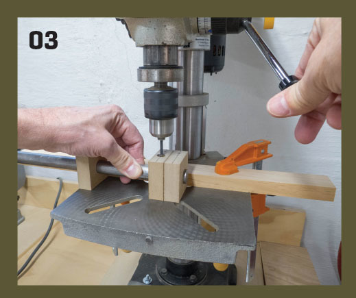 03. The pre-bored MDF blocks are slipped over the bar stock handle, with each centered at their respective locations. A spare block is positioned at the edge of the table to support the free end of the bar. Use cutting fluid or light machine oil while dri