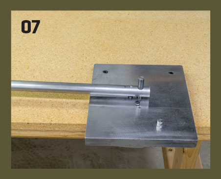 07. The bender should be bolted to a secure work surface. Note that the holes for the 1/4-inch cap screws are counterbored so that the heads are recessed below the surface, allowing clear 360° travel for the bender arm. You can even bend coil-spring landi