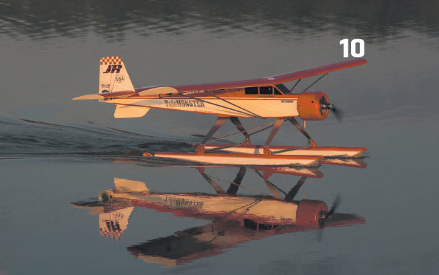 Seen in the sunrise calm at Joe Nall, a 12-foot, gas-powered Telemaster taxis on the lake at Triple Tree Aerodrome in Woodruff SC. The floats are riding deep in the water before the pilot accelerates for takeoff. 