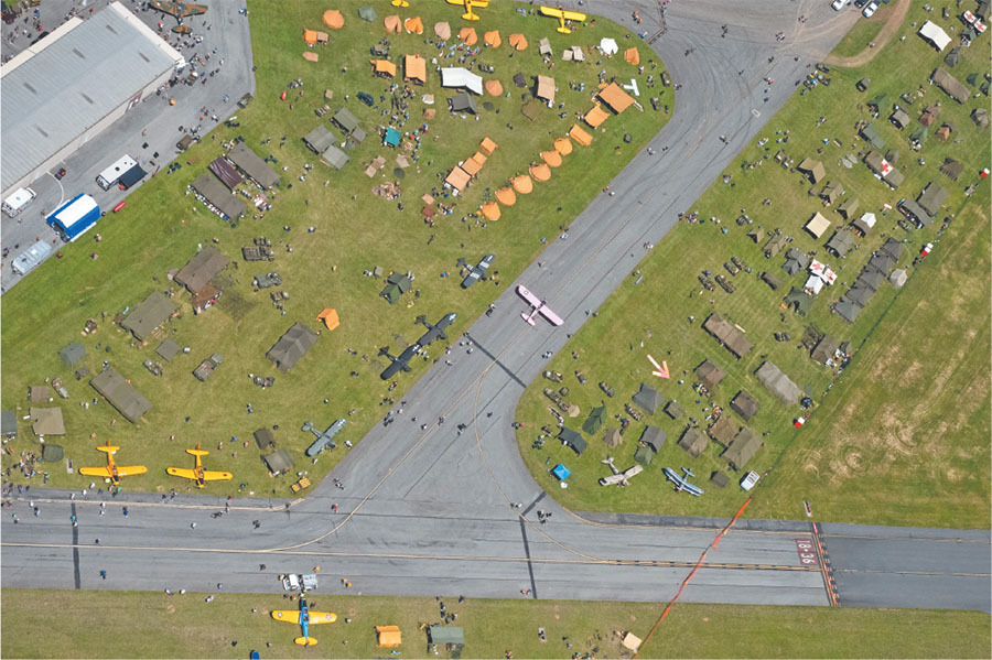 The author piloted the aerial photo flight for the event. This shows just some of the aircraft, vehicles, and WW II tents that were present. The event’s flight photographer, Chad Smith, provided the photo. 