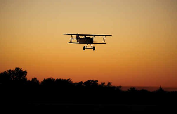 a biplane in the air at sunset over thunder field