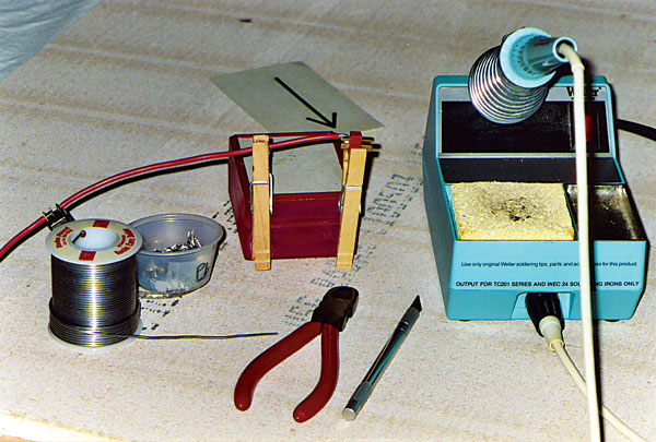 Proper tools for soldering can make the job much safer and easier. Notice the holder for the hot soldering iron and the clothespins that make it simple to hold small parts in proper alignment.