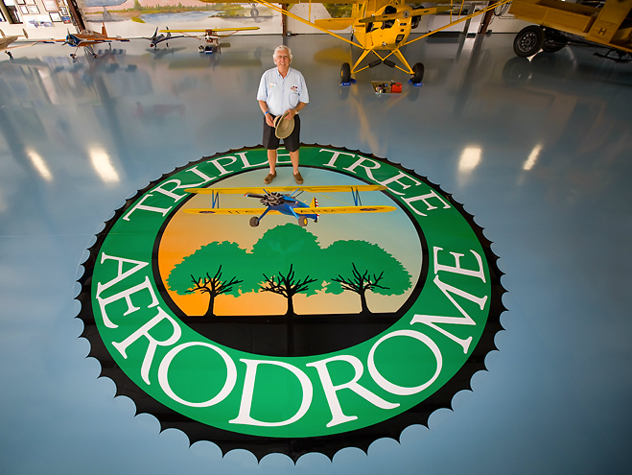 Pat Hartness is standing on the Triple Seal, located in the main hangar where he keeps his restored full-scale airplanes and RC models.
