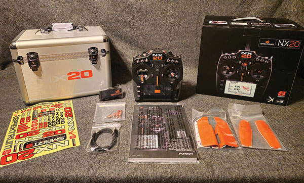 A case, short and long optional stick ends, USB magnetic adapter cable, orange grip set, and a NX20 decal sheet are all included with the radio. 