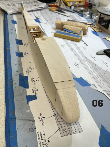 The fuselage is built on a flat bench surface and does not require placing plans underneath. The author likes to have the plans on the work surface for reference. Having the plans under this part of the build also helps to determine the needed pushrod len
