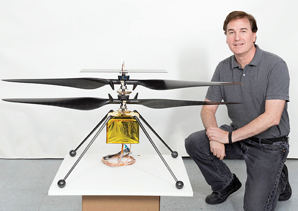 matt poses in his office with one of the mars helicopter engineering models
